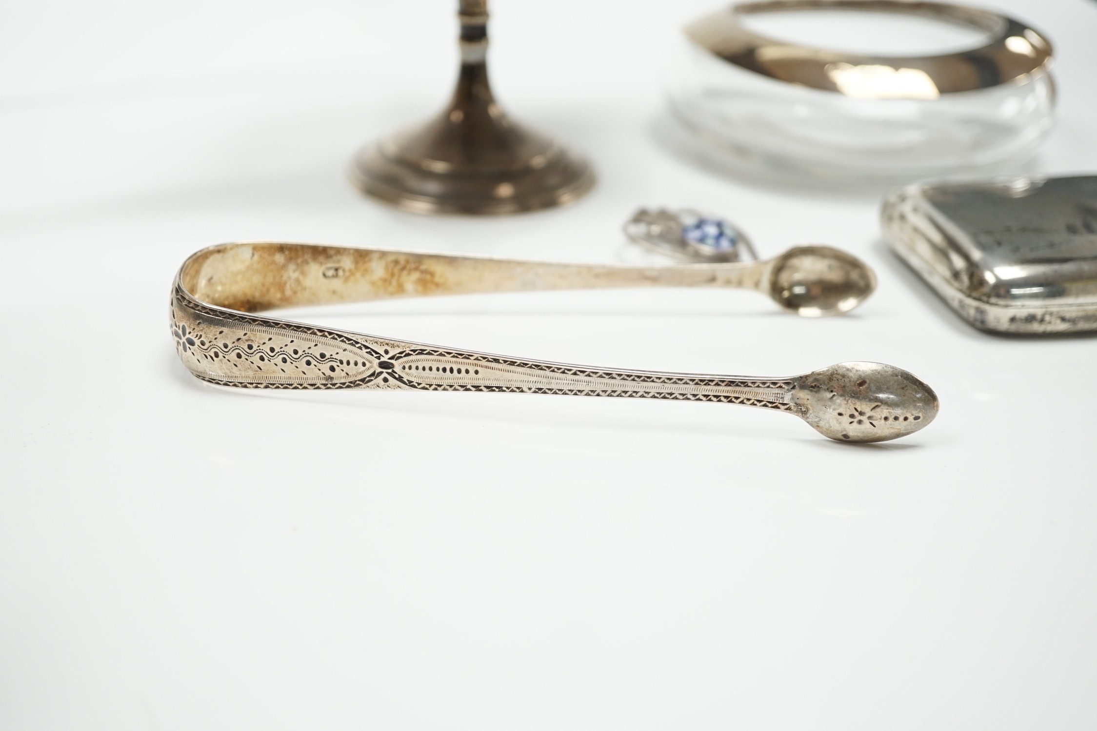 A George V silver tazza, a silver cigarette case, a pair of George III silver sugar tongs, a silver mounted glass shallow dish and a modern silver and lass inset pendant.